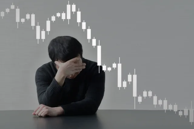 下落するチャートを前に頭を抱える男性